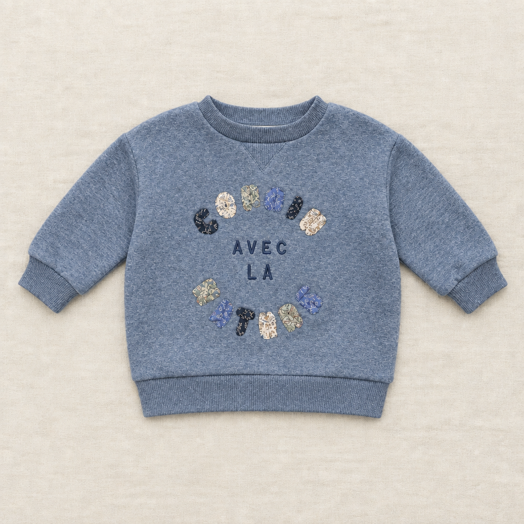 Chandail bébé bleu à col rond, imprimé pattes et texte « AVEC LA »