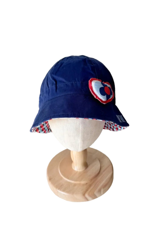 Chapeau bébé bleu avec appliqué cœur multicolore et bordure à motifs.
