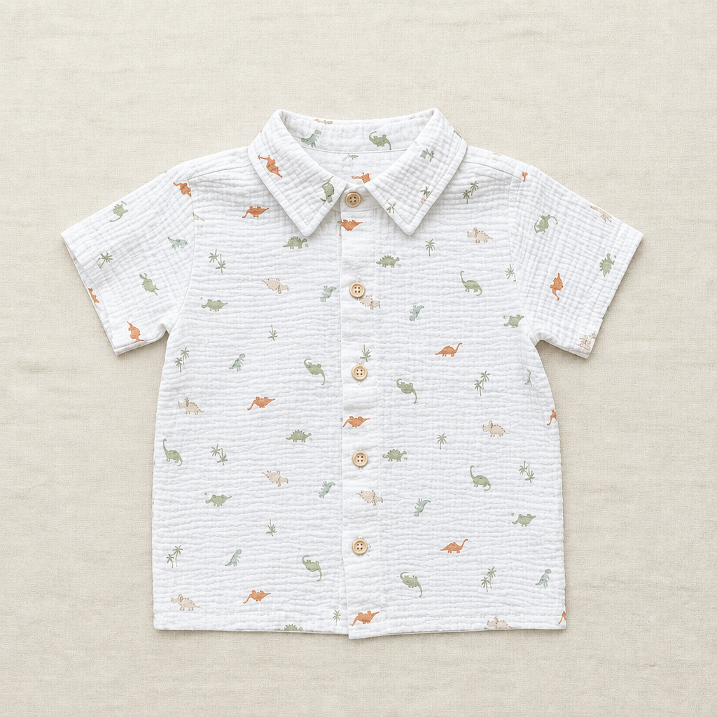 Chemise polo enfant blanche à manches courtes, col boutonné, motif dinosaures multicolore.