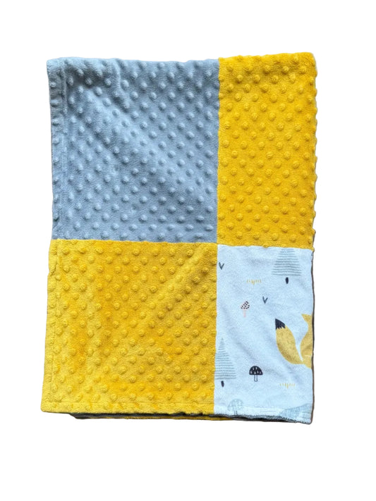 Couverture en minky patchwork bleu clair et jaune, avec motif d’oiseau sur un carré.