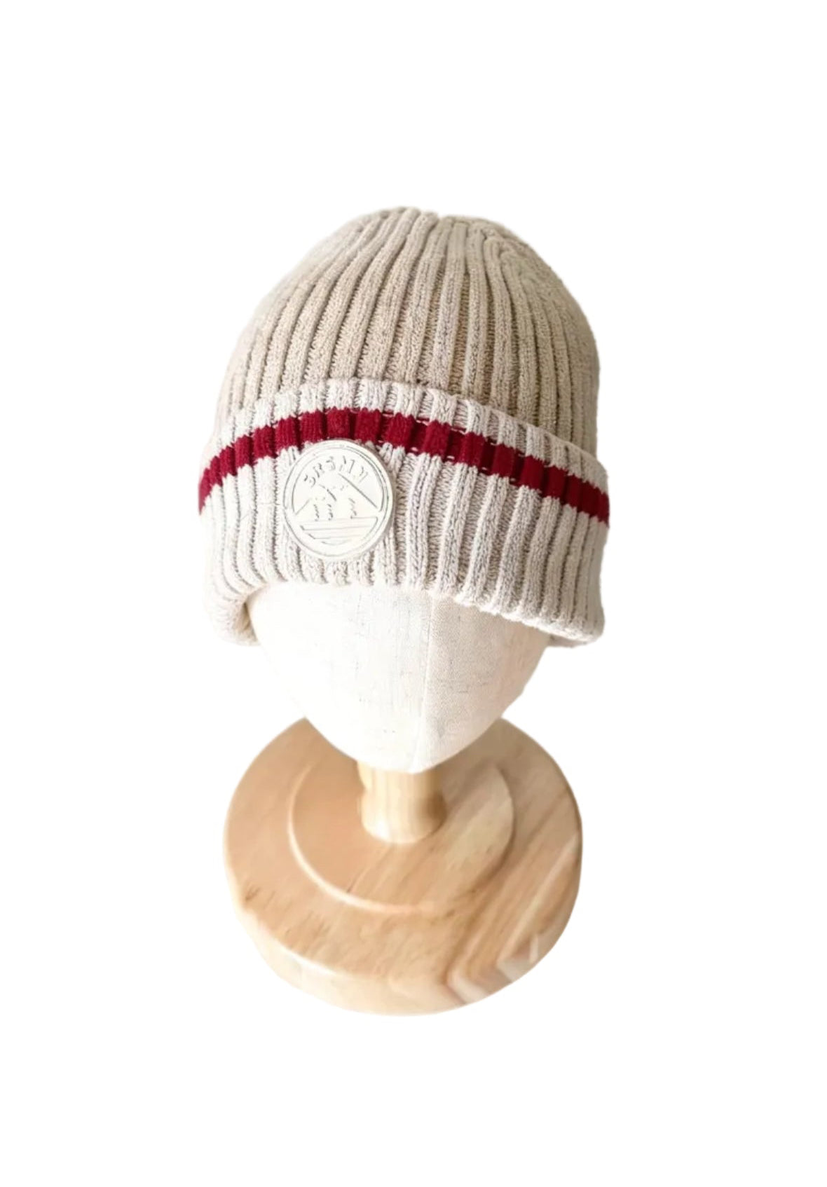 Tuque en tricot beige à rayures rouges et blanches avec écusson rond sur le revers.