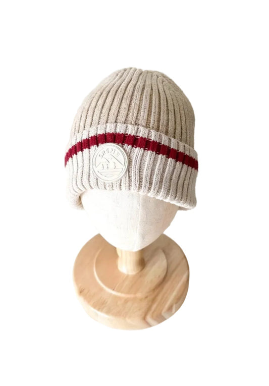 Tuque en tricot beige à rayures rouges et blanches avec écusson rond sur le revers.