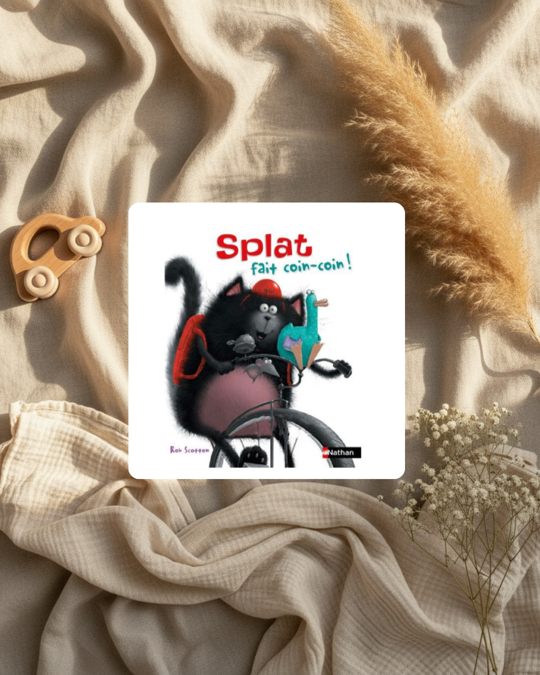 Livre illustré sur tissu beige, couverture avec chat noir au vélo et titre rouge