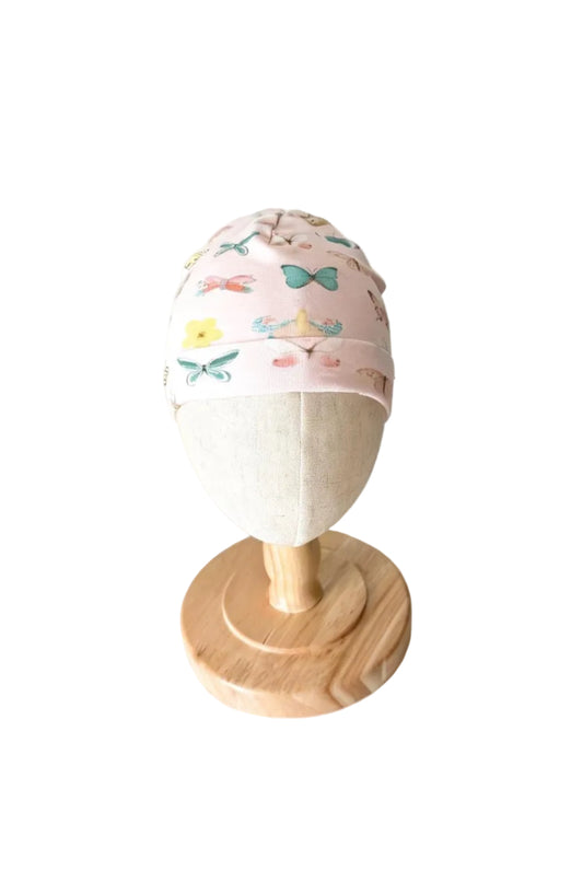 Bonnet bébé rose crème à motifs de papillons et rubans, bordure doublée.