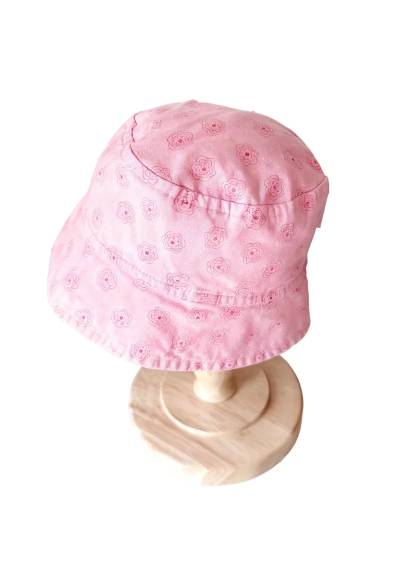 Chapeau bébé rose à motifs fleuris, couture centrale et bord ondulé.