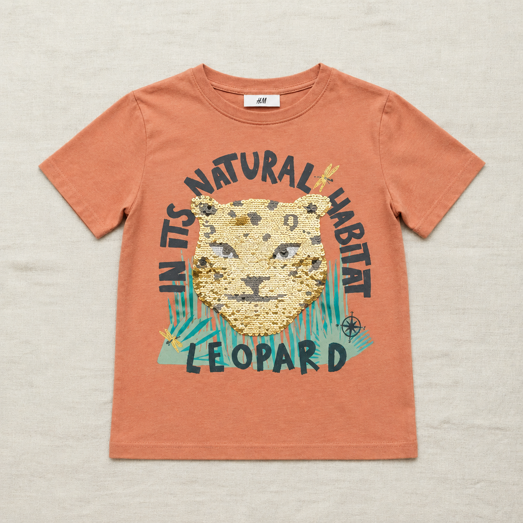 T-shirt enfant H&M orange avec tête de léopard à sequins et texte coloré.