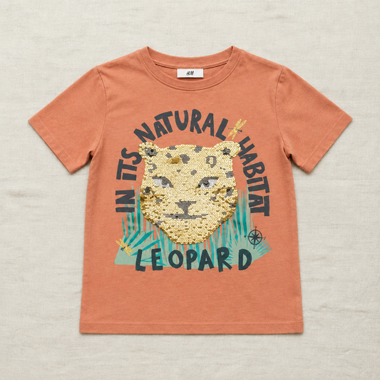 T-shirt enfant H&M orange avec tête de léopard à sequins et texte coloré.